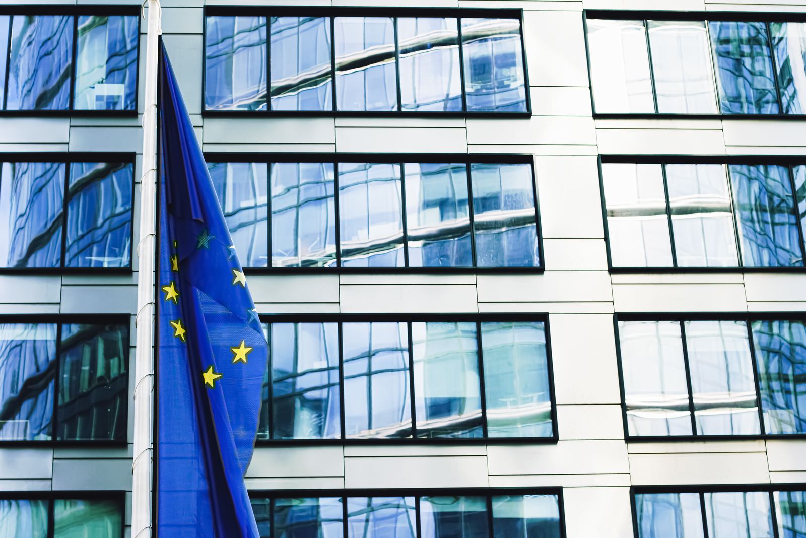 Europaflagge vor einem modernen Bürogebäude – Transparenzpflichten der EU-KI-Verordnung.