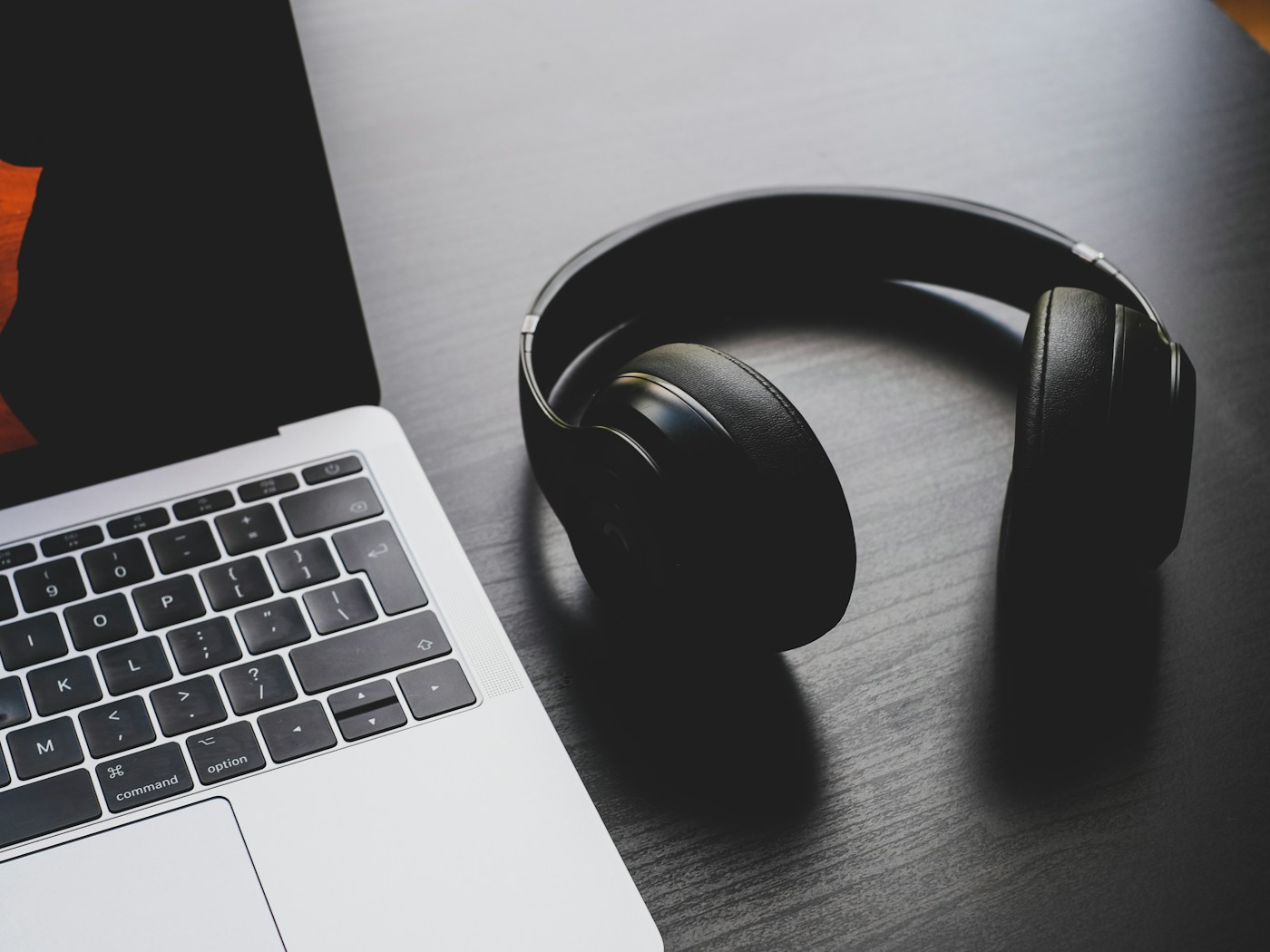 Kopfhörer am Laptop — KI-Telefonansagen selbst erstellen und sofort anhören.