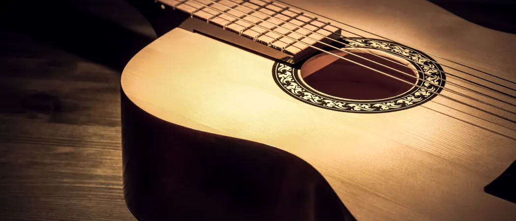 Akustikgitarre auf einer Holzfläche im Lichtstrahl
